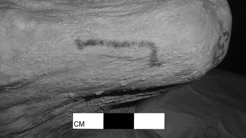 The stick-shaped tattoo on the right arm of Gebelein Woman.